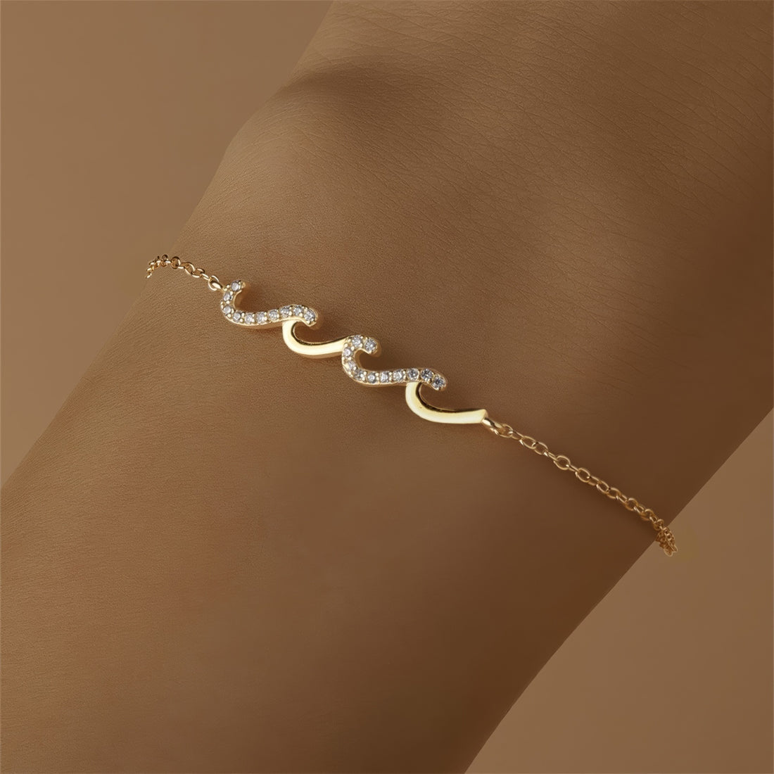 Gold bracelet with wave-shaped zircon design centerpiece on a sterling silver chain, finished with 18K gold plating.