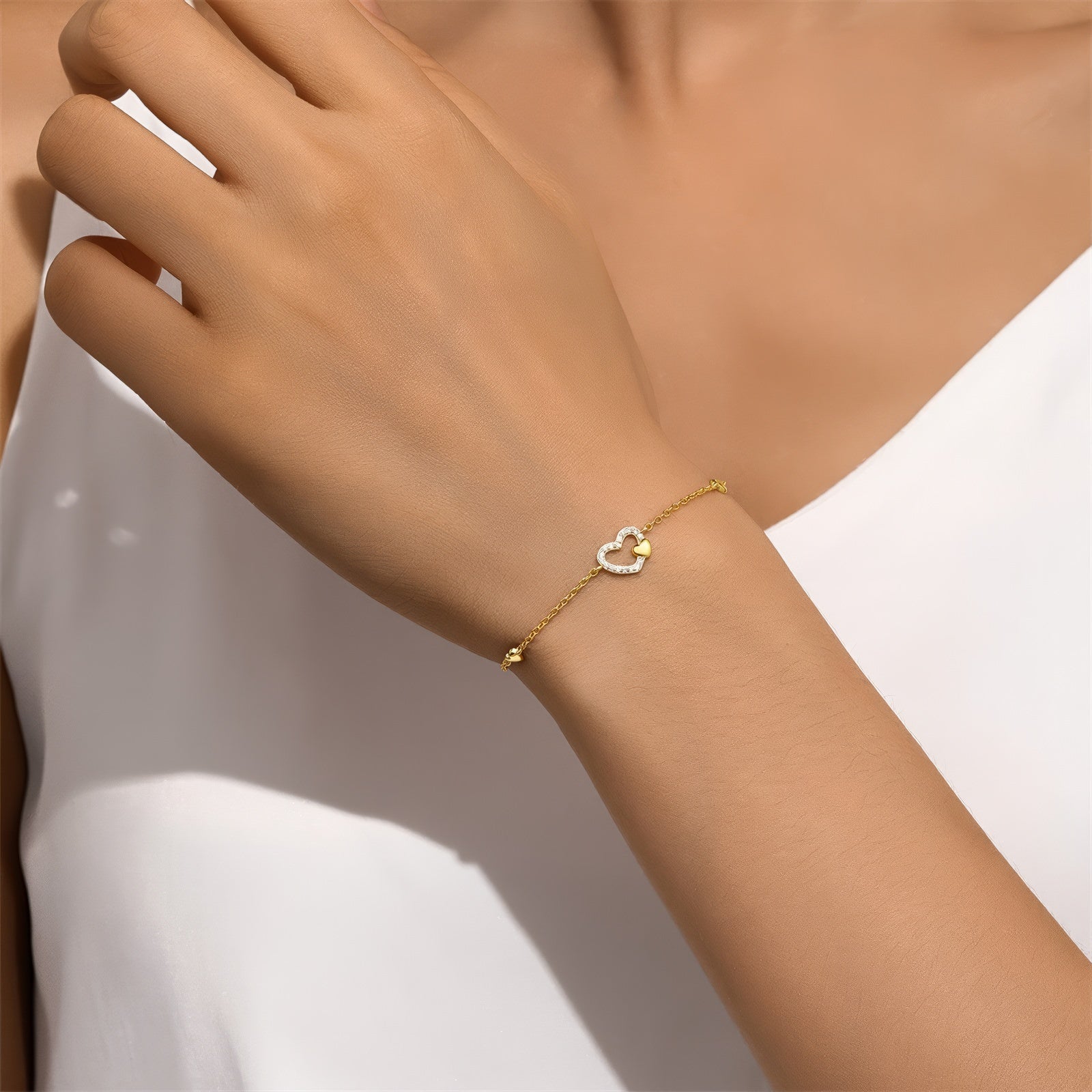 Delicate gold-plated chain bracelet featuring a central heart charm adorned with small zirconia stones, flanked by two tiny heart accents, in polished sterling silver with gold plating