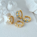 Small hoop earrings with three heart-shaped spokets, each set with sparkling cubic zirconia stone, in 925 sterling silver with gold plating