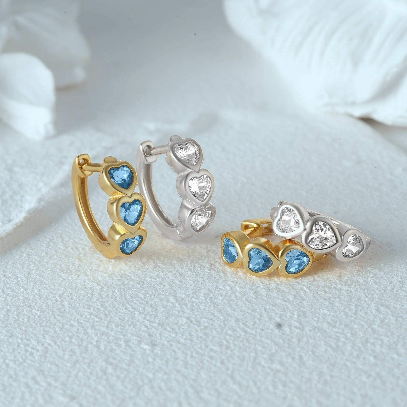 Small hoop earrings with three heart-shaped spokets, each set with sparkling cubic zirconia stone, in 925 sterling silver with gold plating