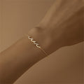 Gold bracelet with wave-shaped zircon design centerpiece on a sterling silver chain, finished with 18K gold plating.