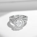 Sterling silver bridal ring set with round-cut moissanite center stone and halo, featuring a pavé split band and matching wedding band with moissanite stones