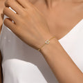 Delicate gold-plated chain bracelet featuring a central heart charm adorned with small zirconia stones, flanked by two tiny heart accents, in polished sterling silver with gold plating